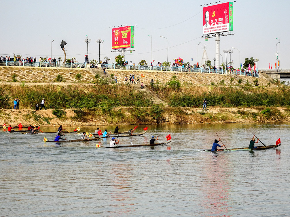 Hình ảnh đua thuyền độc mộc làm bằng gỗ và vận động viên bên bờ sông khu đô thị mới Kon Tum, ảnh Bác Hồ trên biển quảng cáo bảng hiệu hộp đèn Lê Nguyễn Đà Nẵng